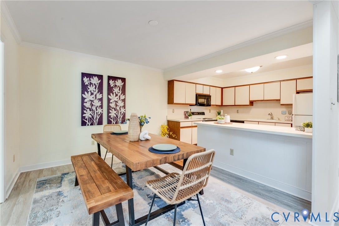 Open-concept kitchen and dining area featuring wood-finish flooring, white cabinetry, a kitchen peninsula with countertop seating, and recessed lighting