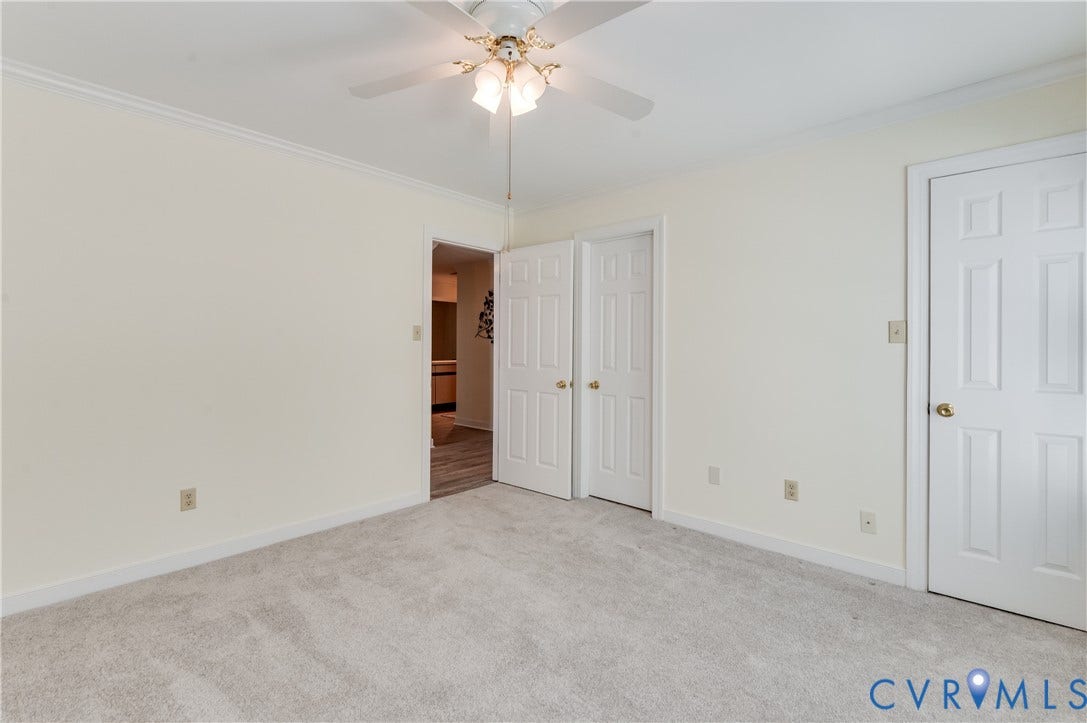Ceiling-mounted fan light fixture, light-toned carpeting, crown molding, and multiple panel doors