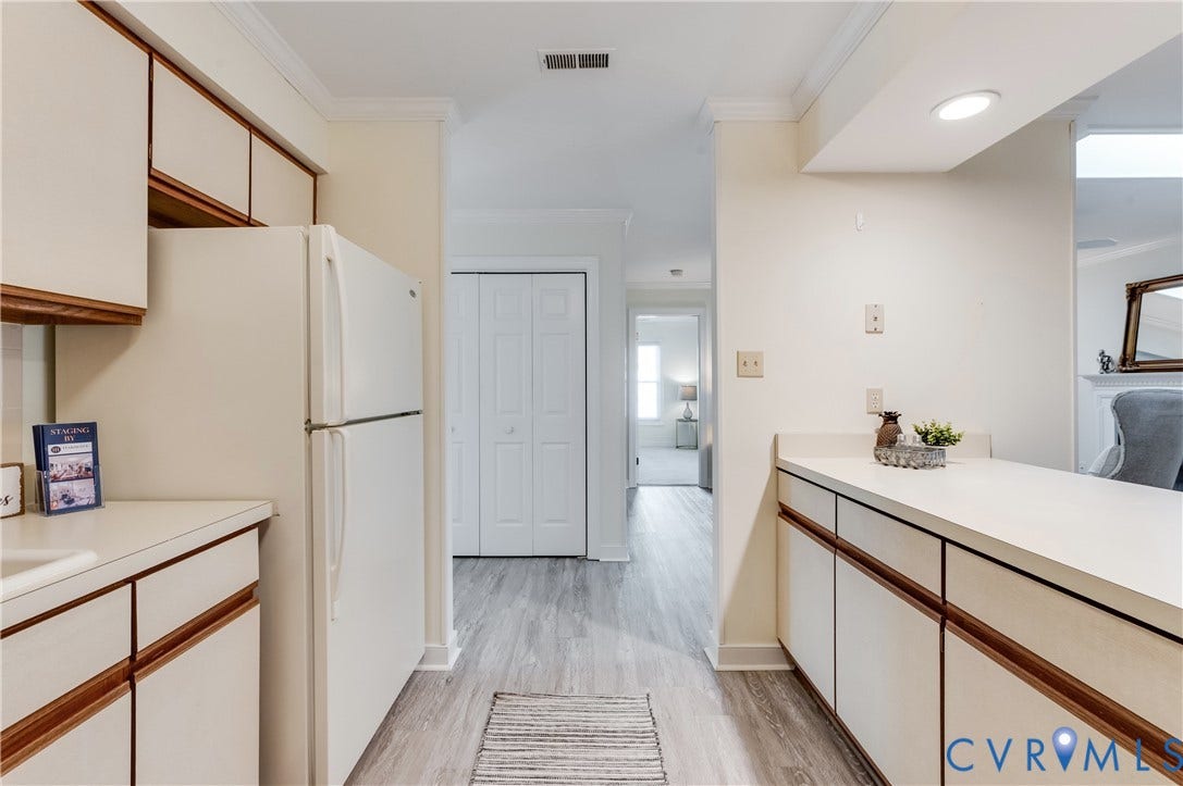 Wood-finish flooring, white cabinetry, white countertops, crown molding, and recessed lighting