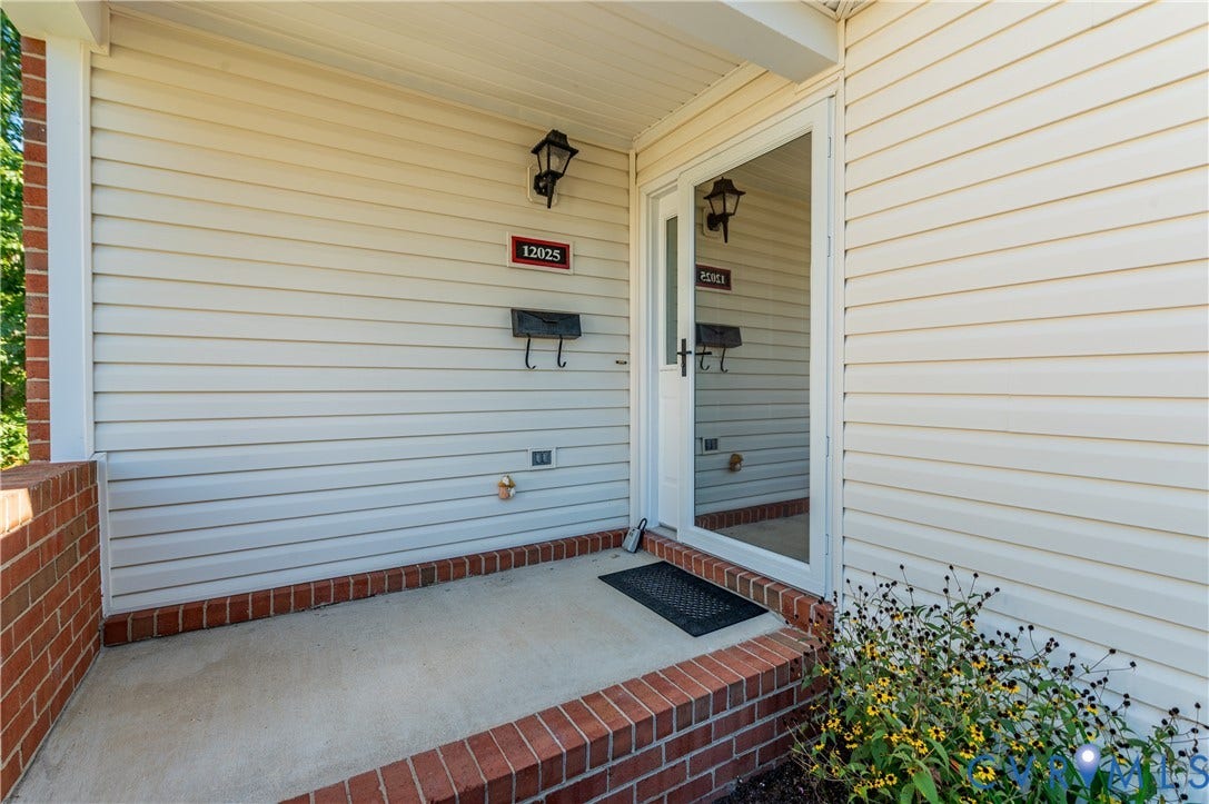 Covered entry porch featuring brick detailing and light-colored siding