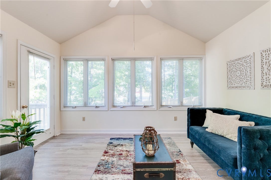 Vaulted ceiling with a ceiling fan, light wood-finish flooring, and multiple windows