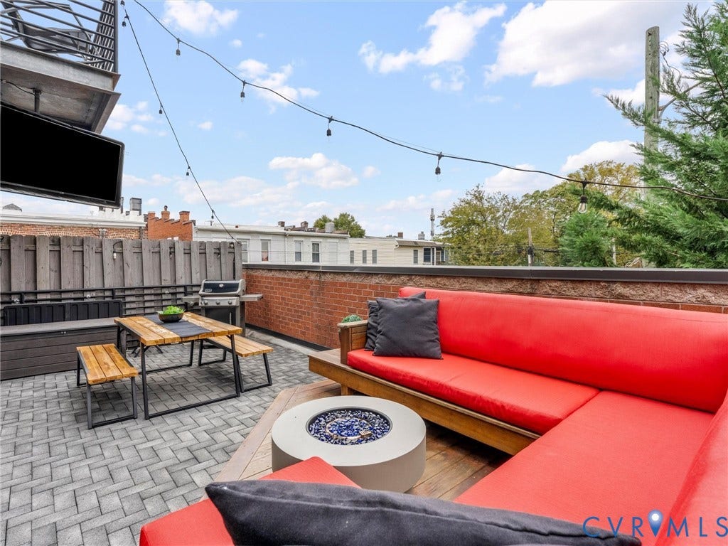 Rooftop terrace with paver flooring, perimeter brick wall, and strung outdoor lighting