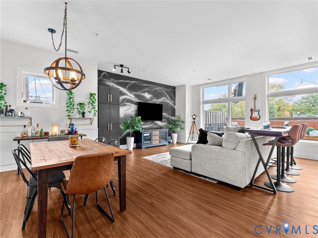 Open concept living space featuring wood-finish flooring, a contemporary spherical chandelier, and a built-in entertainment wall with accent lighting