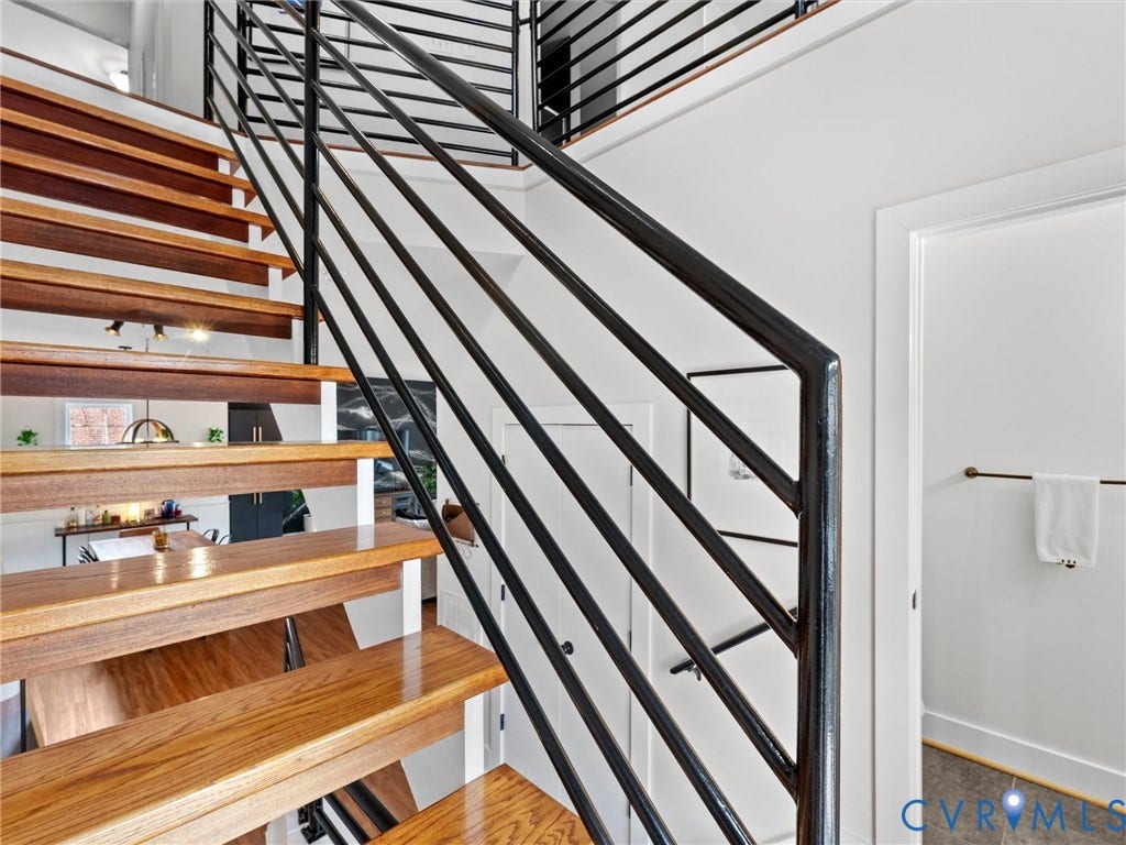 Hardwood staircase with open risers, contemporary metal railing, and white walls