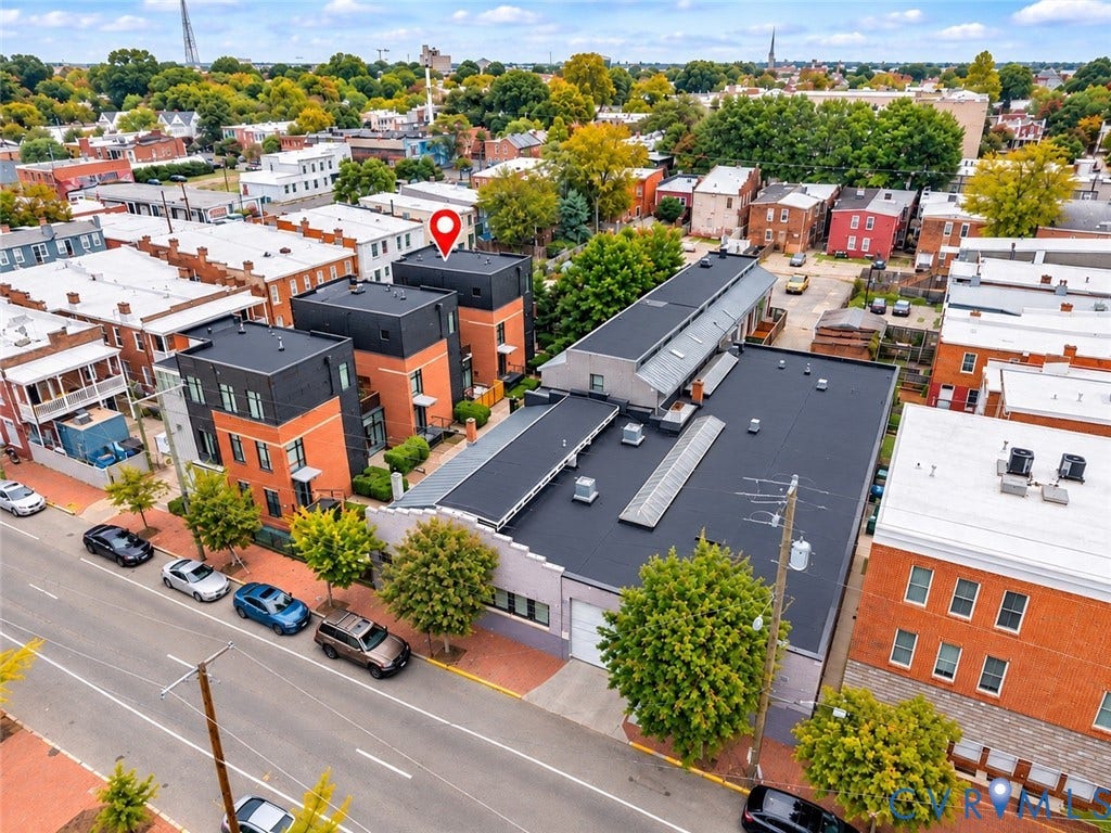 Modern townhome with multi-story construction, brick and dark panel facade, flat roofline, and street-facing windows