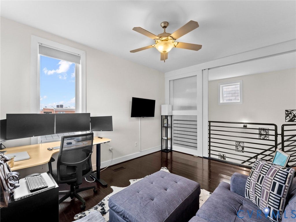 Hardwood flooring, ceiling fan with integrated lighting, expansive window, white trim, and a black wrought iron railing