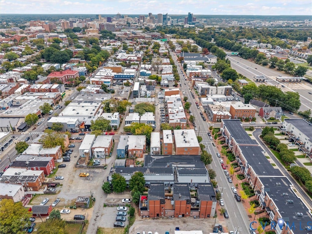 Urban neighborhood setting with varied architectural styles, multi-story brick buildings, and street-level commercial spaces