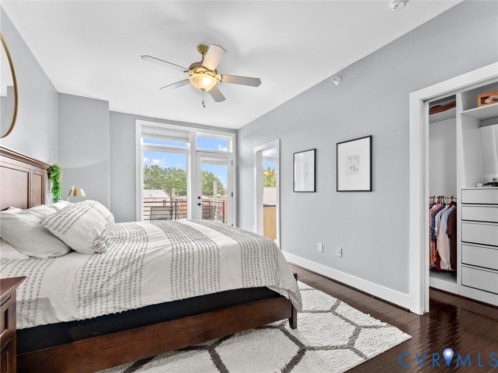 Hardwood flooring throughout, ceiling fan with integrated lighting, glass panel door to an outdoor space, and built-in closet organization system