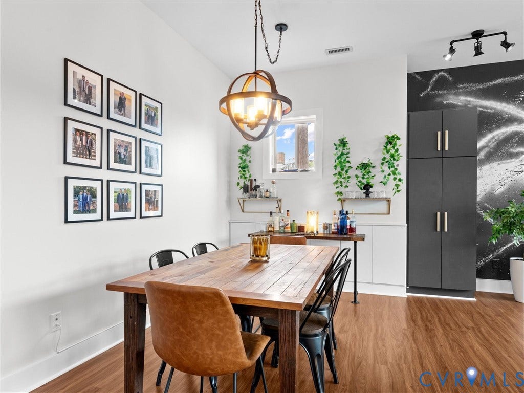 Wood-finish flooring with a rustic dining table, orb-style chandelier, and white walls