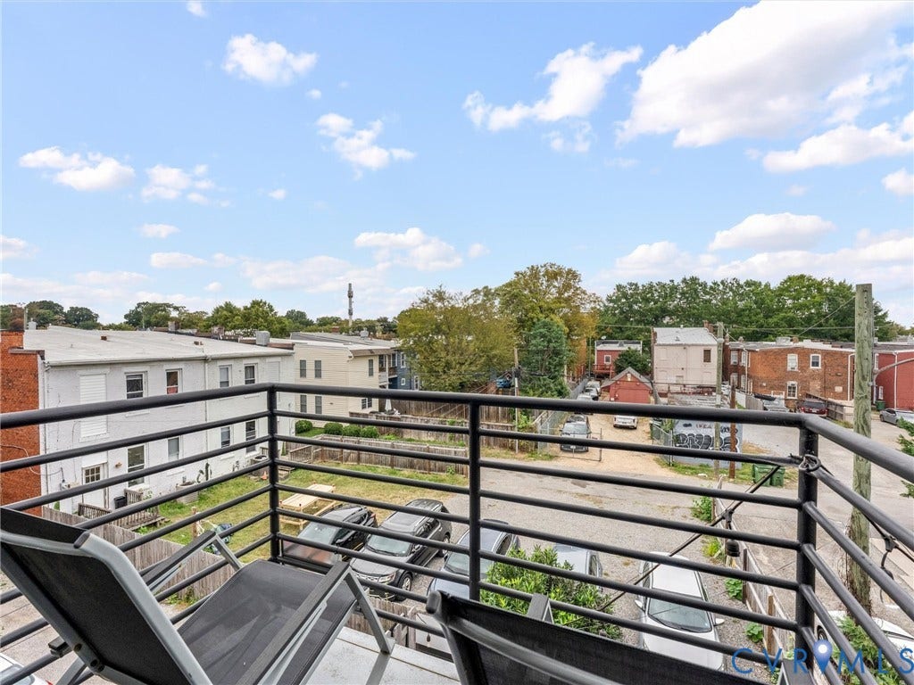 Rooftop balcony featuring black metal railings and broad neighborhood vistas