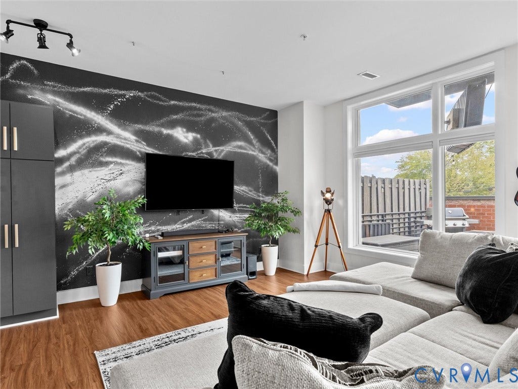 Hardwood-finish flooring, full-height windows, track lighting, and a built-in storage cabinet with gold-tone pulls
