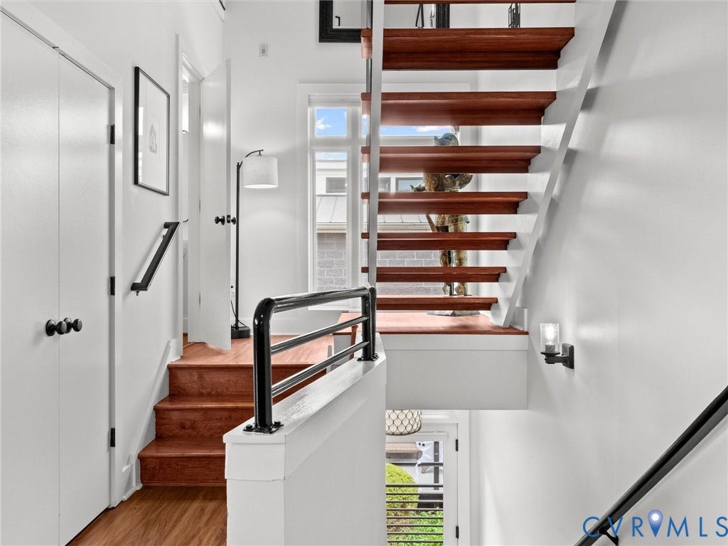Multi-level interior featuring wood-finish stairs, white walls, and black hardware accents