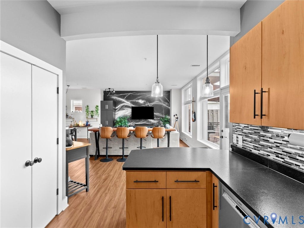 Kitchen featuring wood cabinetry, black countertops, and a mosaic tile backsplash