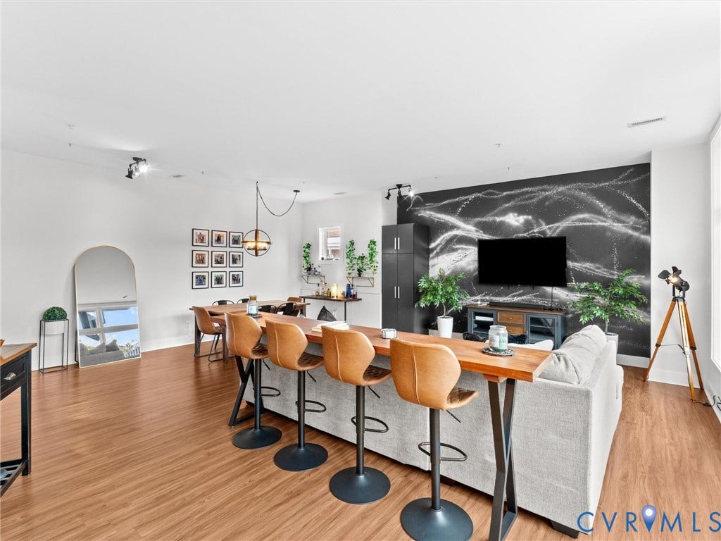 Wood-finish flooring throughout, a distinctive black accent wall, high ceilings, and recessed lighting