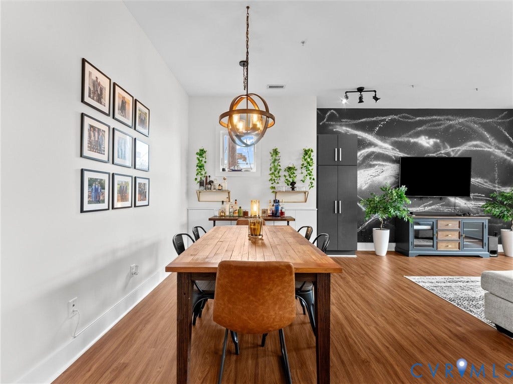 Open-concept living space with wood-finish flooring, a contemporary spherical chandelier, and a decorative accent wall