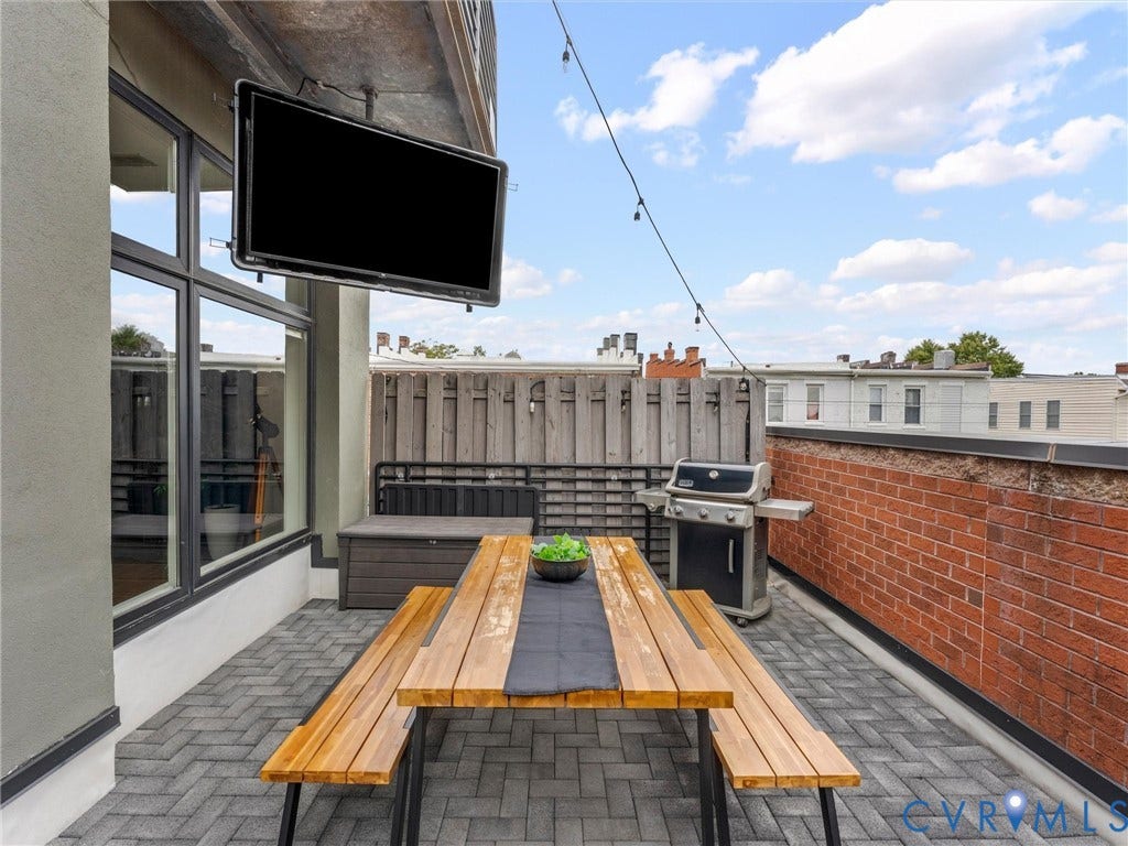 Outdoor terrace with herringbone paver flooring, brick wall, and a privacy fence