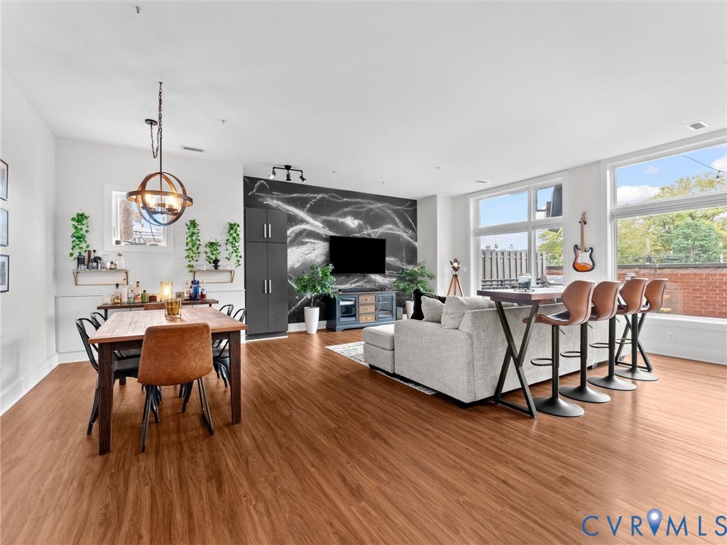 Spacious open-concept living area with abundant natural light, wood-finish flooring, and high ceilings