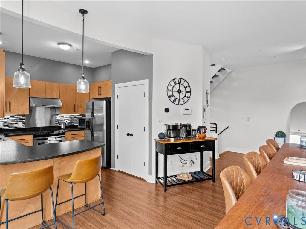 Kitchen featuring wood-finish cabinetry, stainless steel appliances, a tile backsplash, and a breakfast bar with pendant lighting