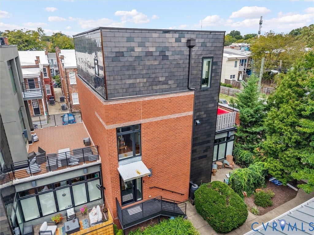 Contemporary exterior featuring brick and dark paneling, multi-level outdoor terraces, and mature landscaping