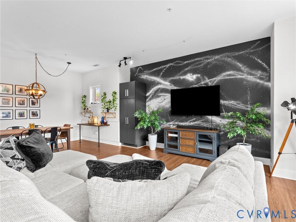 Wood-finish flooring throughout, featuring a distinctive accent wall, built-in storage cabinetry, and a prominent dining area fixture