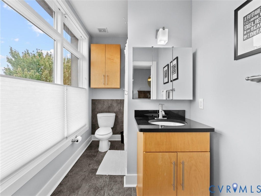 Bathroom featuring a modern vanity with a black countertop, a rectangular undermount sink, and a mirrored medicine cabinet