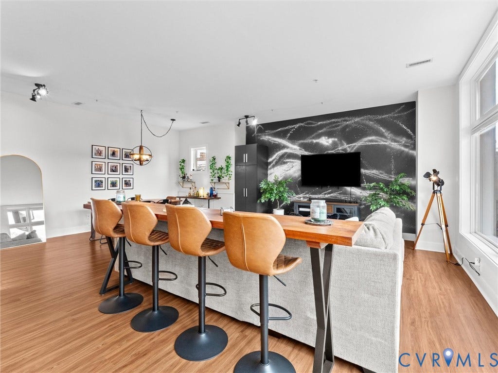 Wood-finish flooring, high ceilings, large windows, recessed and track lighting, and an arched entryway