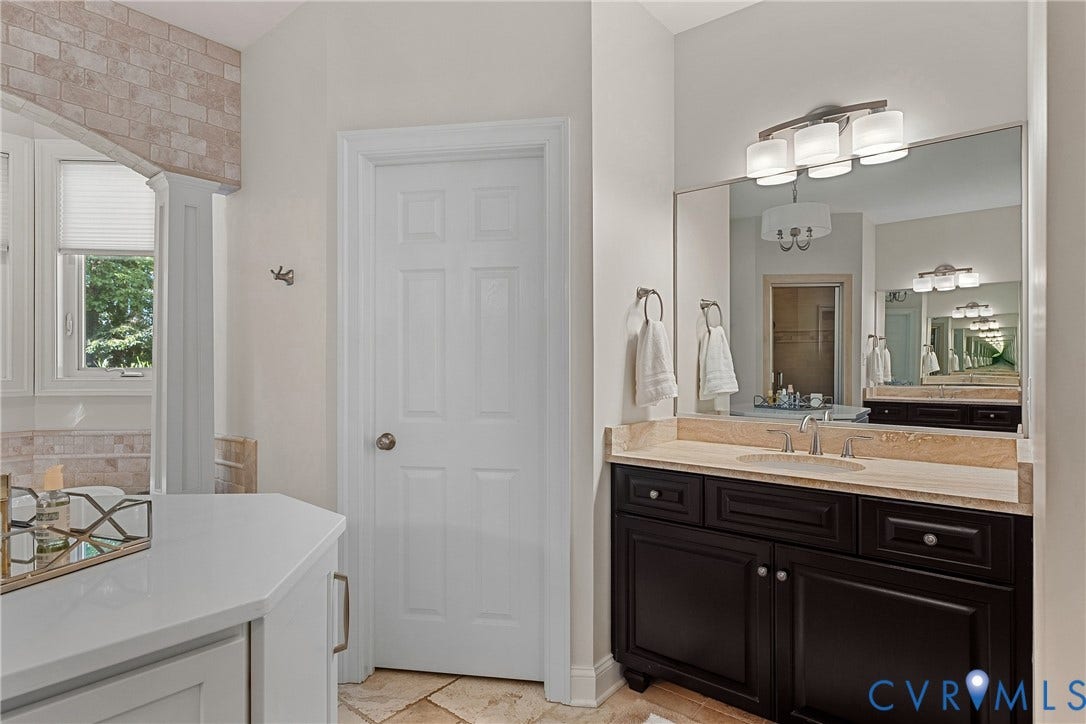 Dual-basin vanity with a light-colored countertop, dark wood-finish cabinetry, and a large wall-mounted mirror