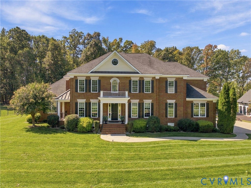 Traditional brick exterior with white trim, a covered entry porch, a side-gabled roof, and a prominent front-facing gable with an arched window