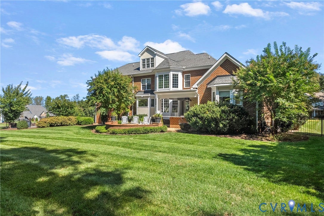 Expansive backyard with a manicured lawn, brick and siding exterior, multi-level deck, and mature landscaping