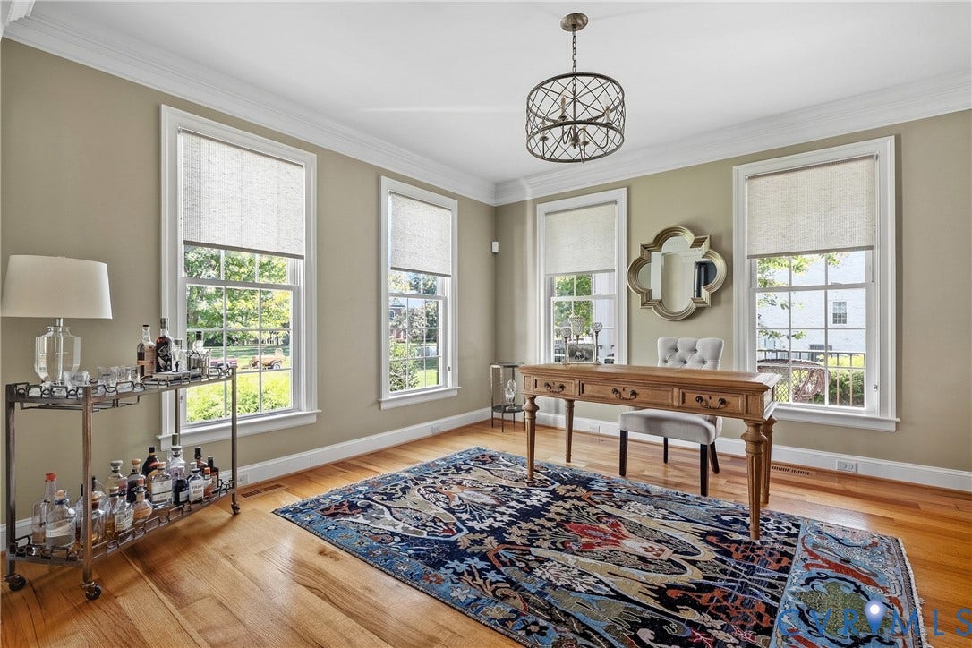 Wood-finish flooring, abundant natural light from multiple windows, crown molding, and a decorative ceiling fixture