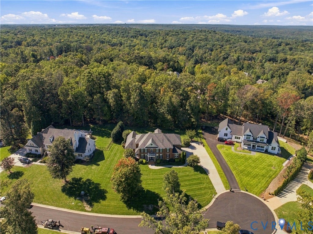 Aerial perspective showcasing multiple properties, extensive landscaping, and mature surrounding trees