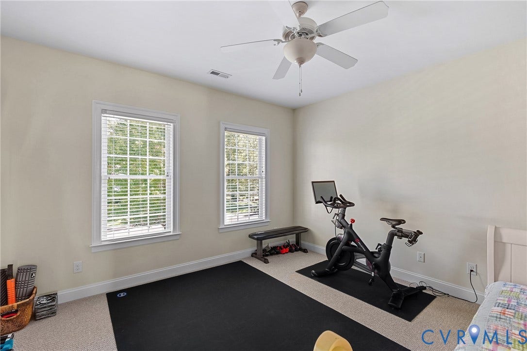 Dual windows with blinds, wall-to-wall carpeting, and a ceiling fan with integrated lighting