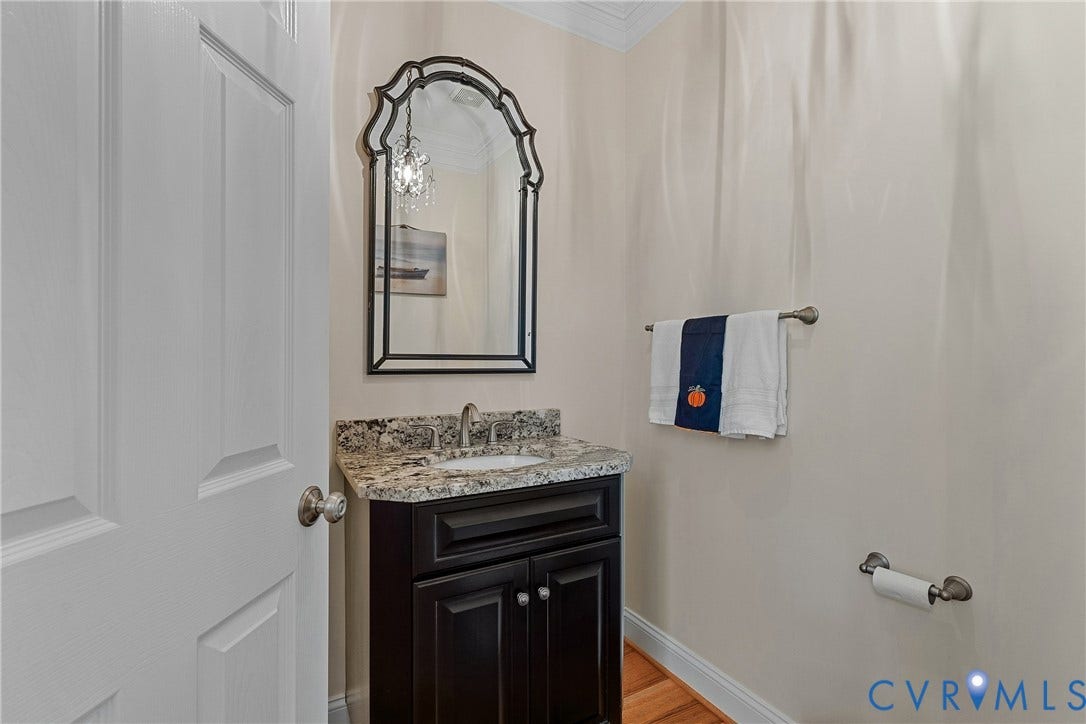 Dark wood-finish vanity with a granite countertop, undermount sink, and brushed nickel faucet