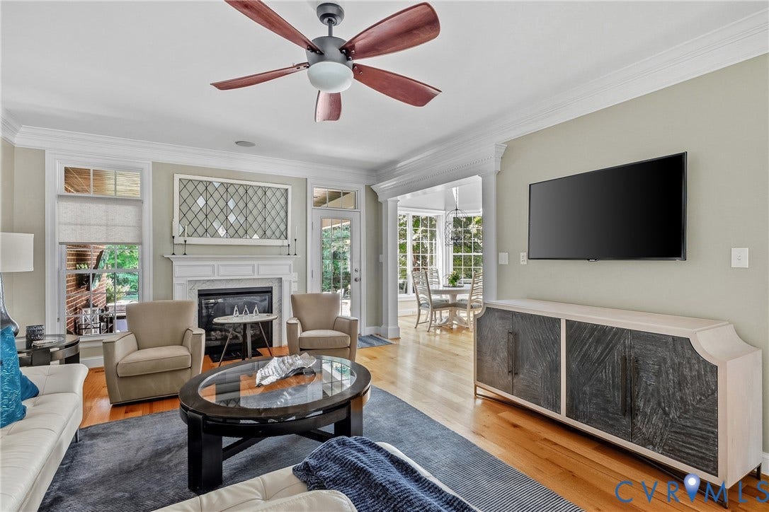 Hardwood flooring, crown molding, built-in fireplace, ceiling fan, and transom windows