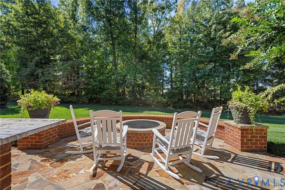 Flagstone patio with a built-in fire pit, brick retaining walls, and a grassy yard