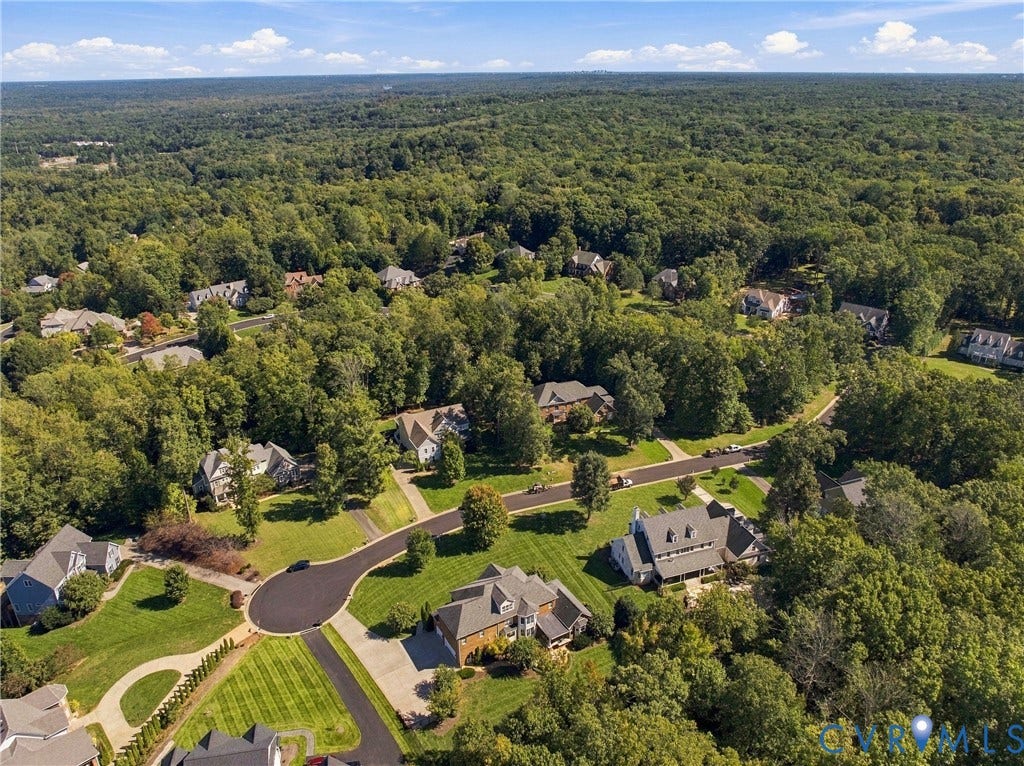 Aerial view showcasing a sprawling estate nestled within mature landscaping and lush tree canopy