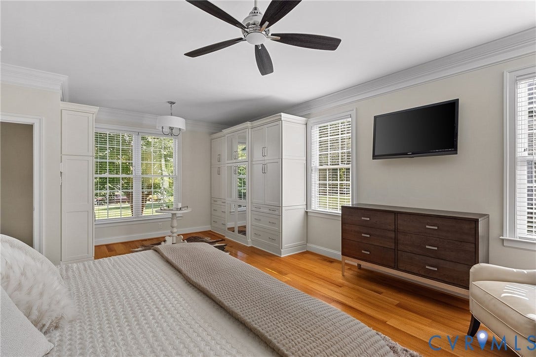 Hardwood flooring, crown molding, built-in cabinetry, multiple windows, and a ceiling fan