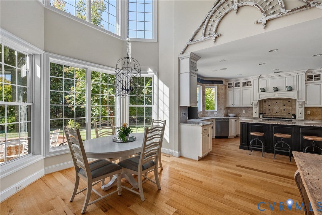 Open-concept living space with abundant natural light, hardwood flooring, and a kitchen featuring a dark-toned island and light-toned cabinetry