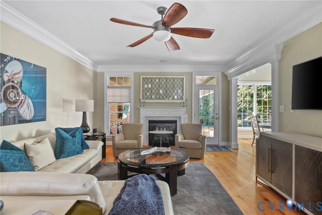 Hardwood flooring, crown molding, a built-in fireplace, a ceiling fan, and an exterior door with glass panels