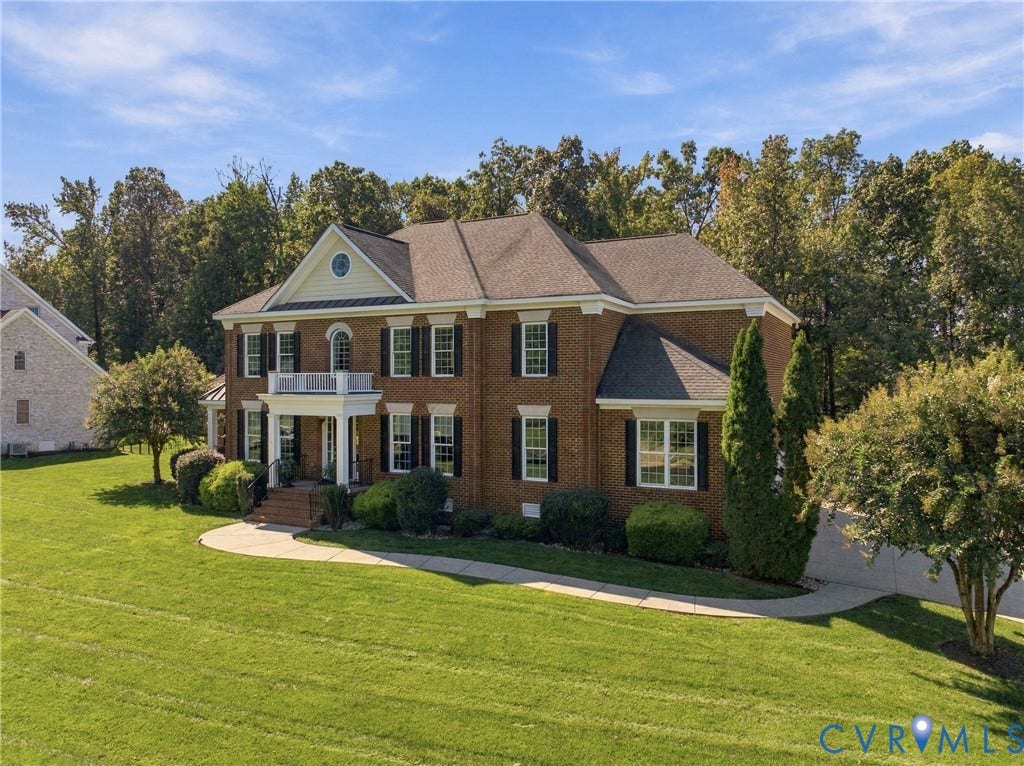 Brick exterior with white trim, a covered front porch, and mature landscaping