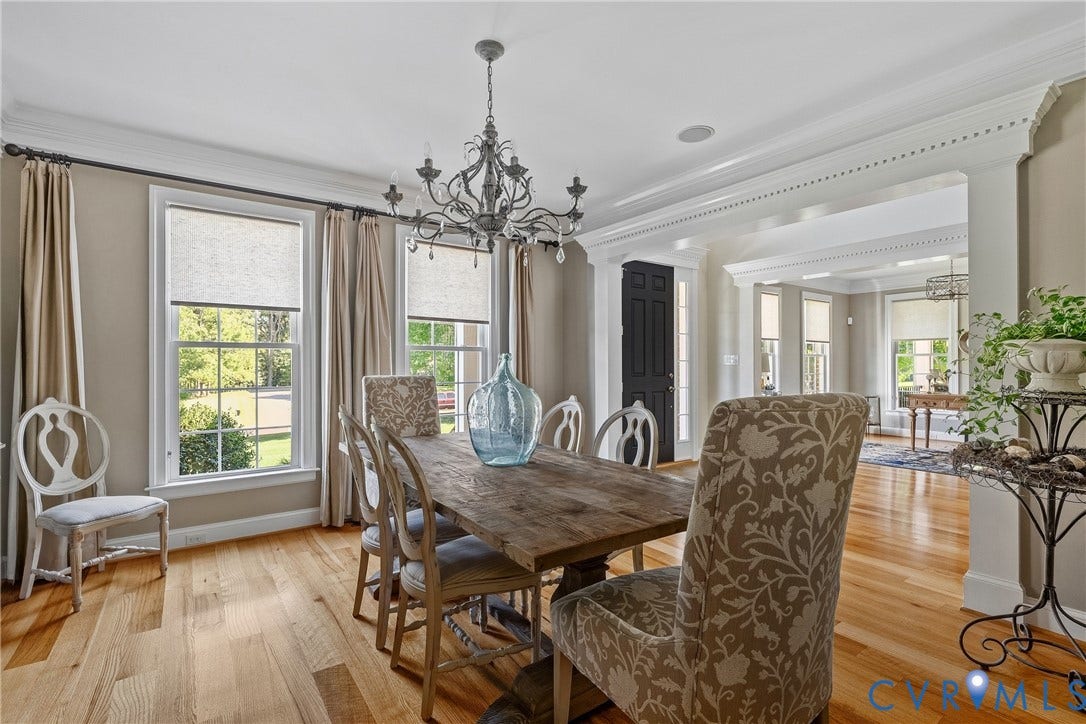 Hardwood flooring throughout, elegant chandelier, decorative crown molding, and multiple windows