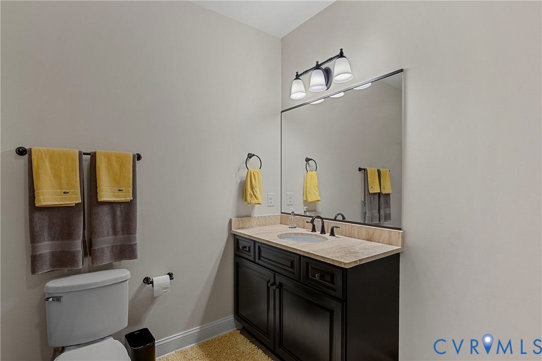 Built-in dark wood-finish vanity with a light-toned countertop, undermount sink, and black-finish faucet