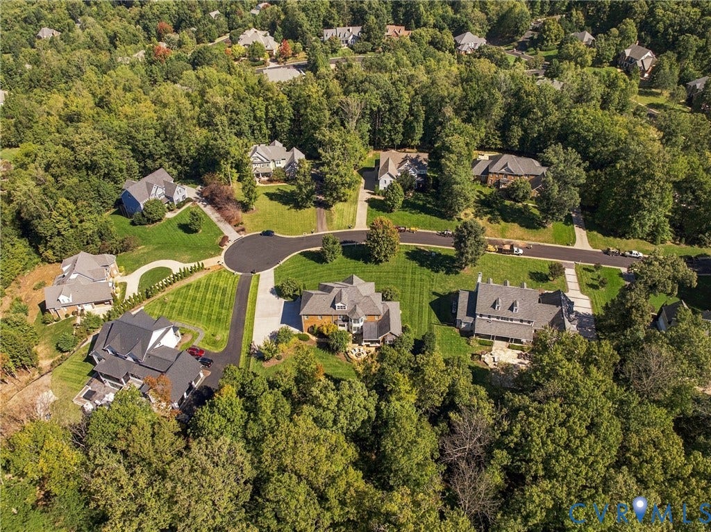 Lush tree canopy surrounds properties featuring manicured lawns and paved driveways