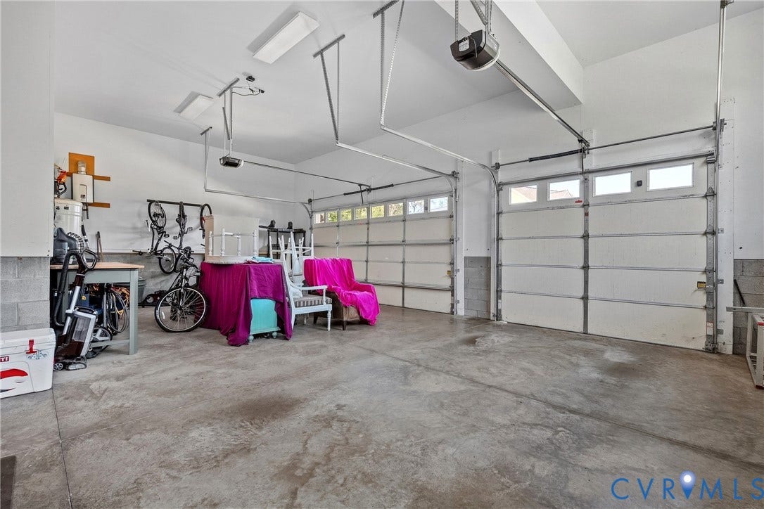 Two-car garage featuring a concrete floor, two automatic garage door openers, and translucent window panels on the garage doors