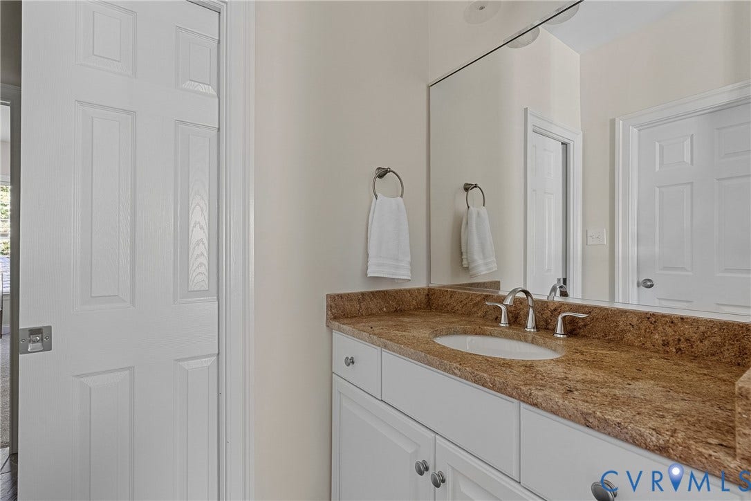 Built-in vanity with a stone countertop, undermount sink, and brushed nickel faucet