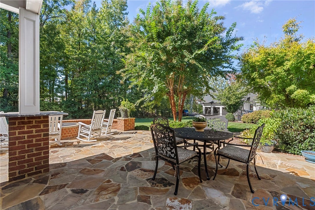 Stone patio with a brick fire pit and lush landscaping