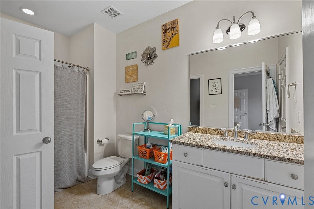 Vanity with a granite countertop, undermount sink, and chrome-finish faucet