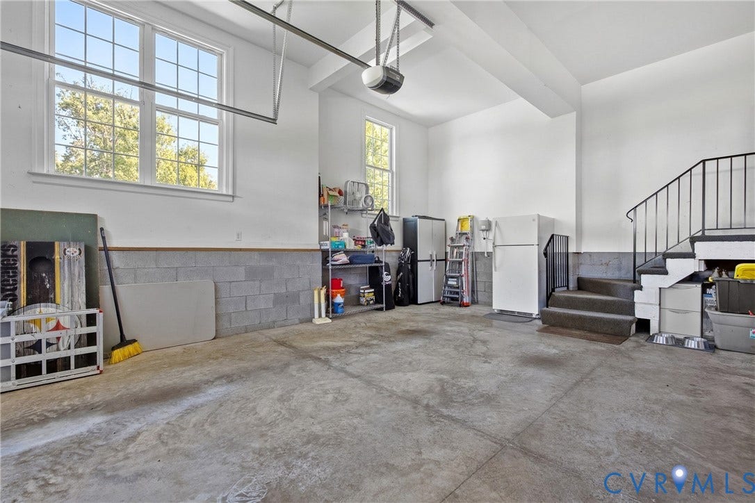 Spacious garage featuring a concrete floor, block wall, and windows with white trim
