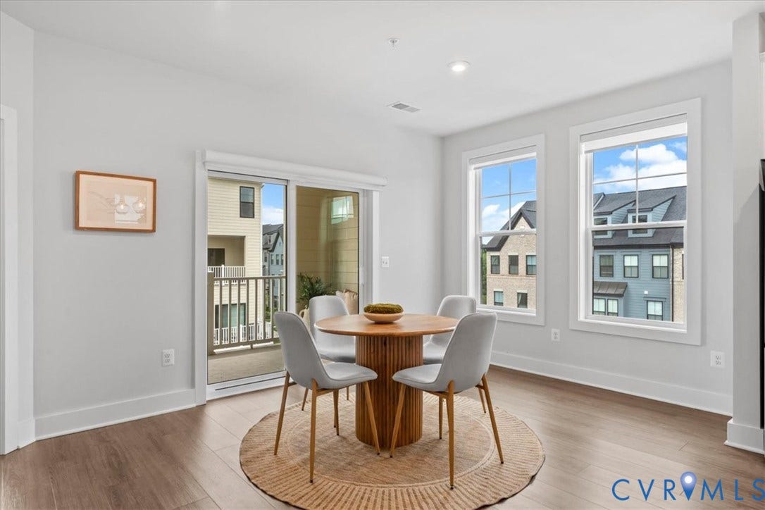 Wood-finish flooring, white walls, two large windows, recessed lighting, and a sliding glass door to an exterior balcony