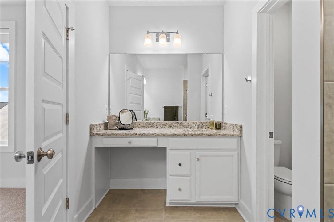 Built-in vanity with a stone-finish countertop, undermount sink, and integrated cabinetry